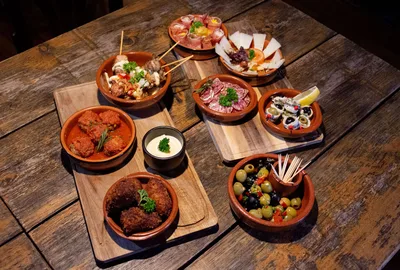 Varias tapas servidas en cazuelas sobre una mesa de madera