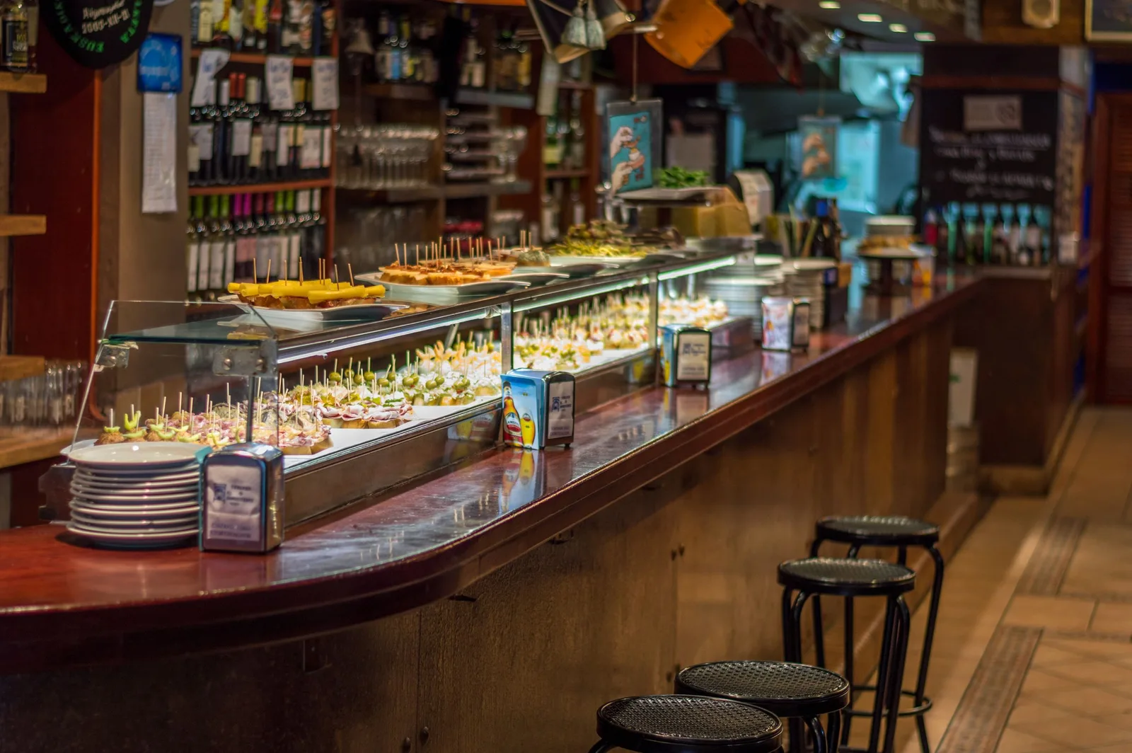 Barra de bar con la vitrina de tapas y taburetes